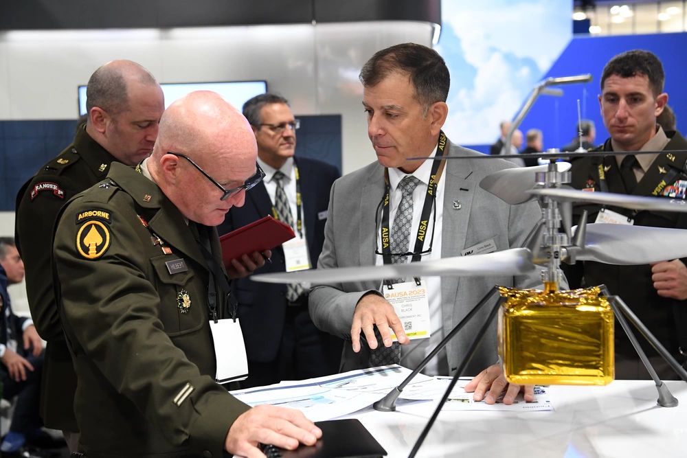 A United States Army general speaking with a contractor at a military trade show in 2023.